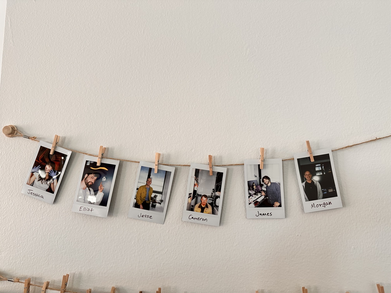 A wall of instant-camera photos, each labeled with a lab community member’s first name