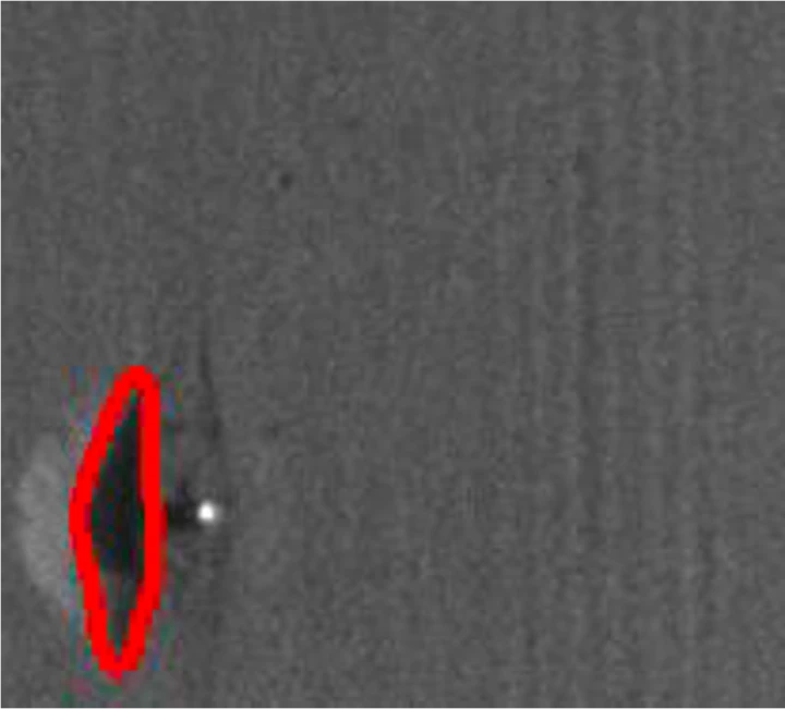 The powder bed after the powder was spread, with a region at the lower left outlined in red beside a bright spot.