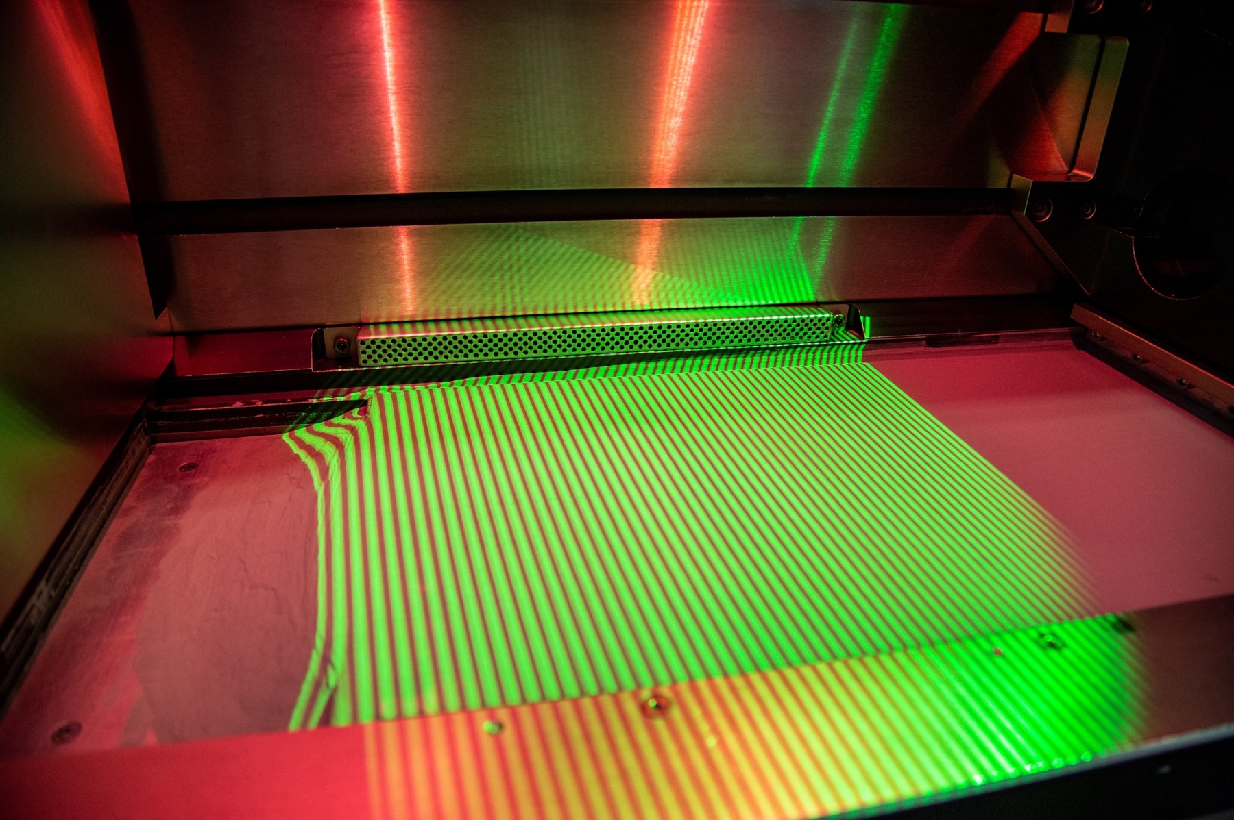 A structured-light fringe pattern projected across the build surface.