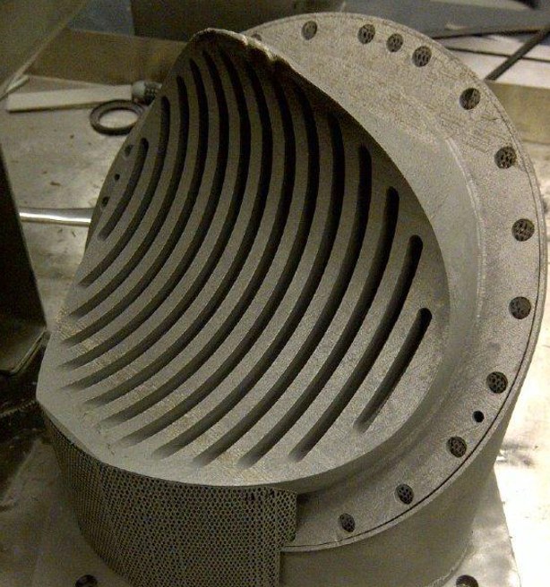 A sectioned additively manufactured component revealing a curved array of internal channels.