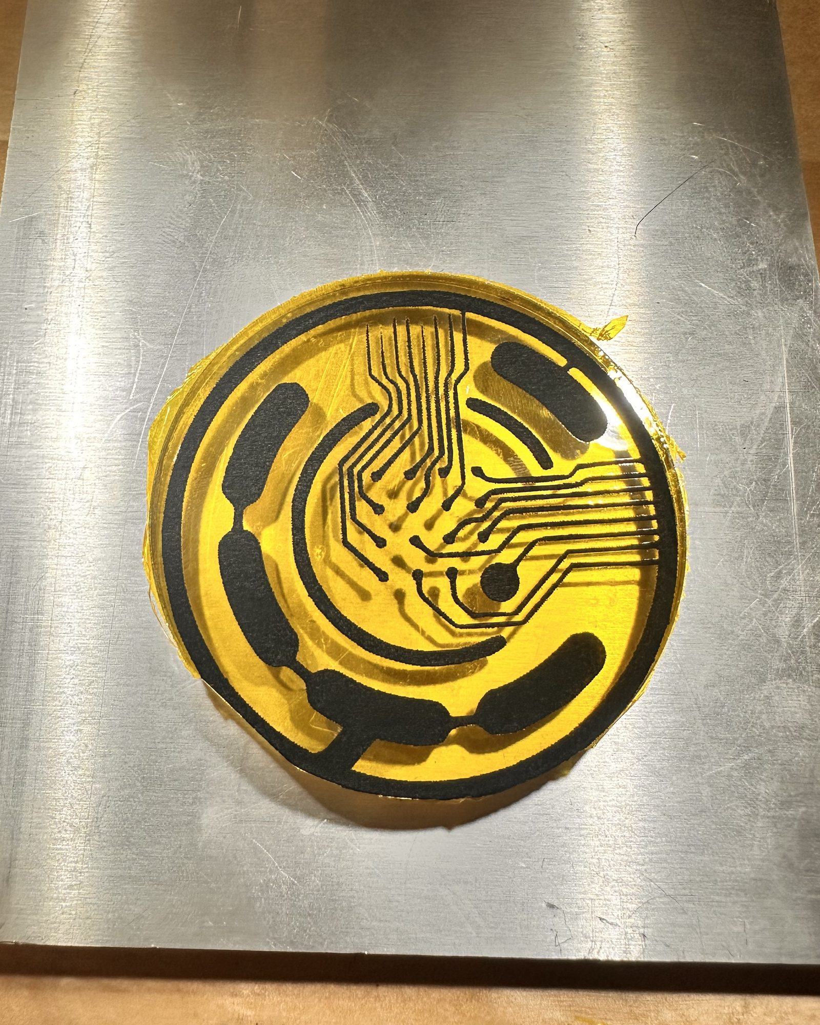 The finished circular Kapton pattern lying on an aluminum plate, its black graphene wires and contact points clearly visible